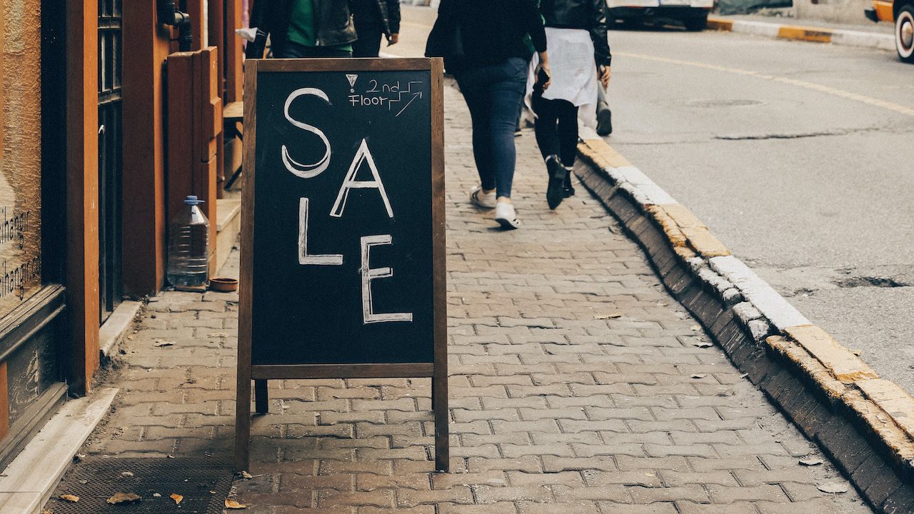 En bild som visar en gatupratare griffel i en stadsmiljö med evenemangsannonsering. Detta visar hur griffeltavlor används för att informera allmänheten.
